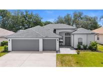 Beautiful single-story home featuring a three-car garage, well-maintained lawn, and neutral color palette at 403 Carriage House Ln, Tarpon Springs, FL 34688