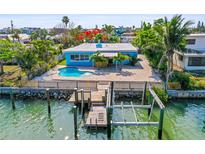 Waterfront home featuring a private dock and boat lift along a tranquil canal with a refreshing pool and vibrant landscaping at 403 Normandy Rd, Madeira Beach, FL 33708