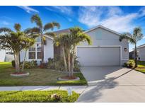 Charming single-story home featuring a well-manicured lawn, lush tropical landscaping, and a spacious two-car garage at 6211 114Th E Dr, Parrish, FL 34219