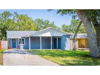 Charming single-story home showcasing a covered carport, blue exterior, and well-maintained front yard, complemented by lush greenery at 7065 73Rd N St, Pinellas Park, FL 33781