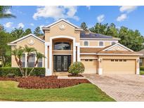 Beautiful two-story tan house with a three-car garage, manicured lawn and solar panels at 10646 Cory Lake Dr, Tampa, FL 33647