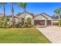 Stunning single-story home with a three-car garage, lush landscaping, and a brick-paved driveway at 10724 Cory Lake Dr, Tampa, FL 33647