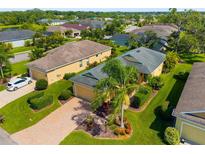 Aerial view of a well-maintained home with lush landscaping, a brick driveway, and a serene neighborhood setting at 11813 Crawford Parrish Ln, Parrish, FL 34219