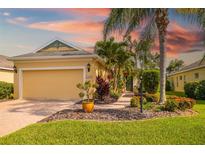 Inviting yellow house showcasing a well-maintained lawn, brick driveway, and mature palm trees, creating a warm curb appeal at 11813 Crawford Parrish Ln, Parrish, FL 34219