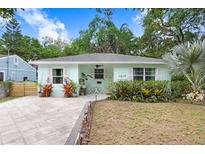 Charming light-blue home with well-manicured lawn, stone pathway, and inviting front porch area at 1213 E Idlewild Ave, Tampa, FL 33604