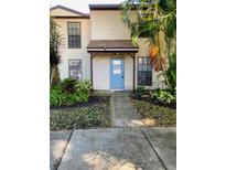 Inviting townhouse featuring a charming blue front door, covered entryway, and lush tropical landscaping at 1515 Bayshore Blvd # 38, Dunedin, FL 34698