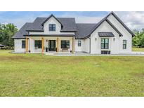 Stunning modern farmhouse with white siding, black trim, and inviting front porch at 17566 Hyland Ln, Dade City, FL 33523