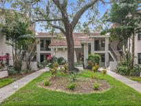 Inviting condo complex featuring lush landscaping and a mature shade tree at 300 S Florida Ave # 600L, Tarpon Springs, FL 34689