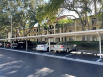 Exterior view of a condominium complex showing parking spaces, trees and landscaping on a sunny day at 3077 Casa Del Sol Cir # 207, Clearwater, FL 33761