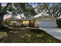 Charming single-story home featuring a manicured lawn, mature trees, and an attached garage, perfect for curb appeal at 5825 Oakhurst Dr, Seminole, FL 33772