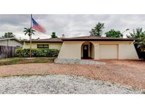 Charming single-story home featuring a brick driveway, landscaped yard, and American flag at 6409 41St N Ave, St Petersburg, FL 33709
