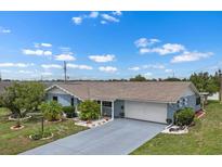 Beautiful blue home with a well-maintained lawn and gray driveway at 1205 Desert Hills Dr, Sun City Center, FL 33573