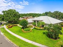 Charming home featuring a beautifully landscaped front yard, lush green lawn, and mature trees, perfect for curb appeal at 13608 Lytton Way, Tampa, FL 33624