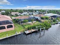An aerial view shows this waterfront home, screened pool, boat dock, and surrounding lush landscaping at 18702 Van Nuys Cir, Port Charlotte, FL 33948