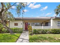Charming one-story home featuring a red door, a white picket fence, and lush green landscaping at 190 Dale Pl, Oldsmar, FL 34677
