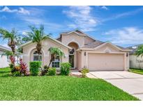 Charming home featuring a two-car garage and beautifully landscaped front yard with palm trees, perfect for curb appeal at 30445 Tremont Dr, Wesley Chapel, FL 33543