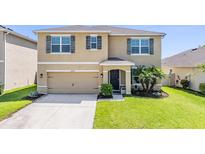 Inviting two-story home featuring a well-maintained lawn, and a two-car garage at 30989 Summer Sun Loop, Wesley Chapel, FL 33545