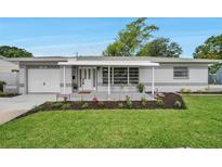 Charming home featuring a cozy front porch, well-maintained lawn, and beautiful landscaping at 3100 70Th N St, St Petersburg, FL 33710