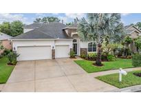 Charming home featuring a well-manicured lawn, mature tree, and three-car garage at 31331 Anniston Dr, Wesley Chapel, FL 33543