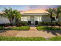 Charming villa with well-maintained landscaping, lush green lawn and mature palm trees at 3410 Stonehaven E Ct # A, Palm Harbor, FL 34684