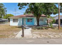 Charming single-story home featuring a light blue exterior, a cozy front yard, and a concrete walkway leading to the front door at 8525 N Ola Ave, Tampa, FL 33604