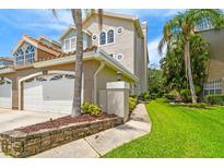 Beautiful multi-story home featuring manicured lawn, an attached garage, and tropical landscaping at 1676 Arabian Ln, Palm Harbor, FL 34685