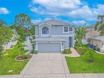 Charming two-story home with a well-manicured lawn, attached garage, and beautiful architectural details at 1807 Split Fork Dr, Oldsmar, FL 34677