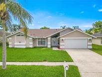 Charming single-story home with manicured lawn, lush landscaping, and a two-car garage at 1838 Eagle Ridge Blvd, Palm Harbor, FL 34685