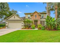 Inviting two-story home with stone facade, lush landscaping, and a well-manicured lawn at 3000 Naughton Way, Tarpon Springs, FL 34688
