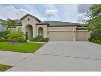 Stunning single-story home featuring a three-car garage, landscaped yard, and an arched entryway at 6016 Shadowlake Dr, Apollo Beach, FL 33572