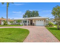 Charming single-story home featuring a brick driveway, manicured lawn, and attached garage at 715 45Th Ne Ave, St Petersburg, FL 33703