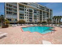 Exterior shot of the building and blue pool deck surrounded by brick and lawn chairs at 7932 Sailboat Key S Blvd # 506, South Pasadena, FL 33707