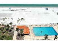 Stunning aerial view of pool and beachside property with sparkling ocean waters and the words, 