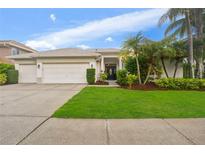 Charming single-story home featuring a three-car garage, well-manicured lawn, and lush tropical landscaping at 9402 Woodbay Dr, Tampa, FL 33626
