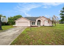 Charming one-story home featuring a two-car garage, well-manicured lawn, and a basketball hoop on the side at 12214 Buckingham Way, Spring Hill, FL 34609