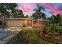 Charming single-story home with lush landscaping, stone accents, and a well-manicured front yard at twilight at 2063 Ridgecrest Dr, Dunedin, FL 34698