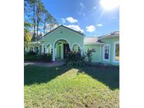 Charming single-story home features a lush front lawn and elegant arched entryway with double doors at 27752 Ravens Brook Rd, Wesley Chapel, FL 33544