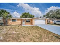 Charming single-story home featuring a front yard, attached garage, and desert-friendly landscaping at 9100 Lunar Ln, Port Richey, FL 34668