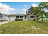 Charming single-story home featuring a well-maintained lawn and a tidy front garden at 2020 Douglas Ave, Dunedin, FL 34698
