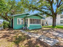 Charming cottage-style home with a screened-in porch and mature trees in a residential neighborhood at 302 W Curtis St, Tampa, FL 33603