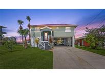 Charming raised beach house with a red roof, palm trees, and a spacious driveway at 4137 Des Prez Ct, Hernando Beach, FL 34607