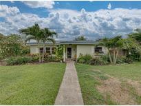 Charming single-story home featuring a lush landscaped front yard, brick path, and vibrant tropical foliage at 6202 7Th S Ave, Gulfport, FL 33707