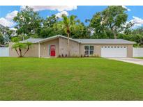 Charming single-story home with a well-manicured lawn, stone accents, and a vibrant red front door at 704 Childers Loop, Brandon, FL 33511