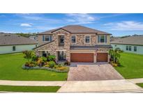 Beautiful two-story home with stone accents, three-car garage, manicured lawn, and colorful landscaping at 9136 Warm Springs Cir, Parrish, FL 34219