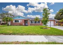 Charming brick home with a well-manicured lawn, vibrant foliage, and a two-car garage at 13296 88Th N Ave, Seminole, FL 33776