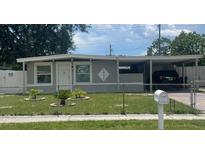 Charming single-story home with a carport, well-maintained lawn, and a white picket fence at 1335 Waikiki Way, Tampa, FL 33619