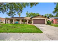 Charming one-story home featuring a brown two-car garage, well-maintained lawn, and inviting front porch area at 2329 Carrie Ct, Dunedin, FL 34698