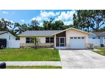 Charming single-story home featuring a well-manicured lawn, stone accents and attached garage at 6460 101St N Ave, Pinellas Park, FL 33782