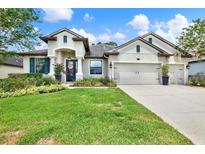 Charming single-story home with a manicured lawn, flowering shrubs, and a three car garage at 679 Challice Dr, Spring Hill, FL 34609
