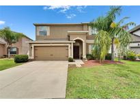 Charming two-story home featuring a well-manicured lawn, arched front door, and a spacious two-car garage at 12316 Streambed Dr, Riverview, FL 33579